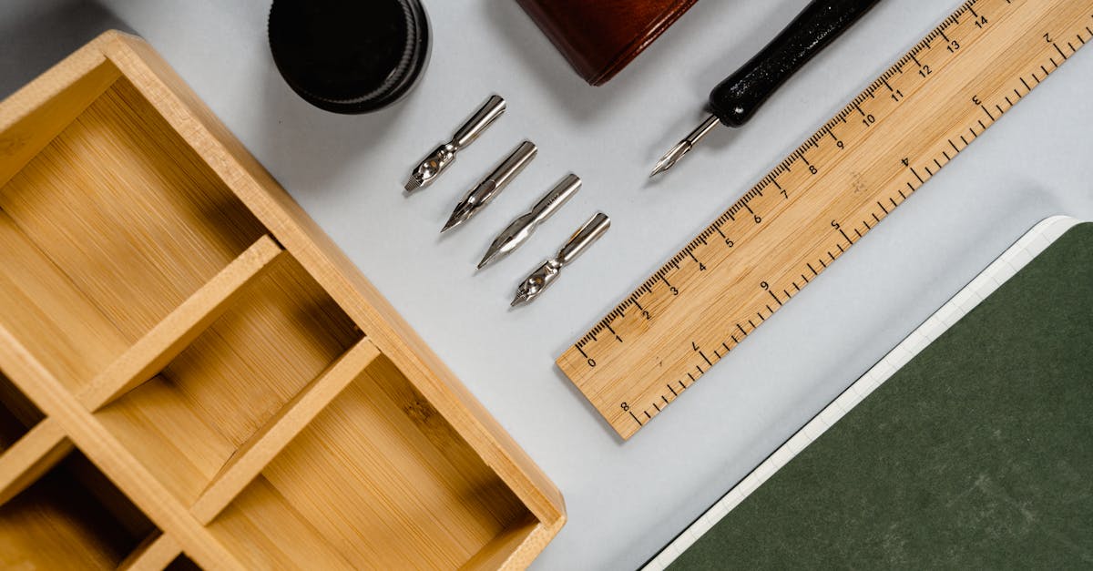 Flat lay of vintage stationery including ink, pen nibs, and a wooden ruler on a desk.