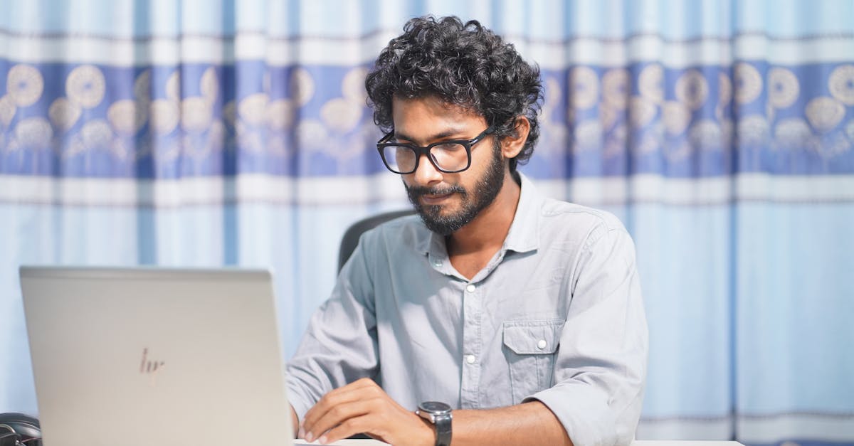 A focused young man using a laptop in a well-lit room. Ideal for themes of productivity and tech.