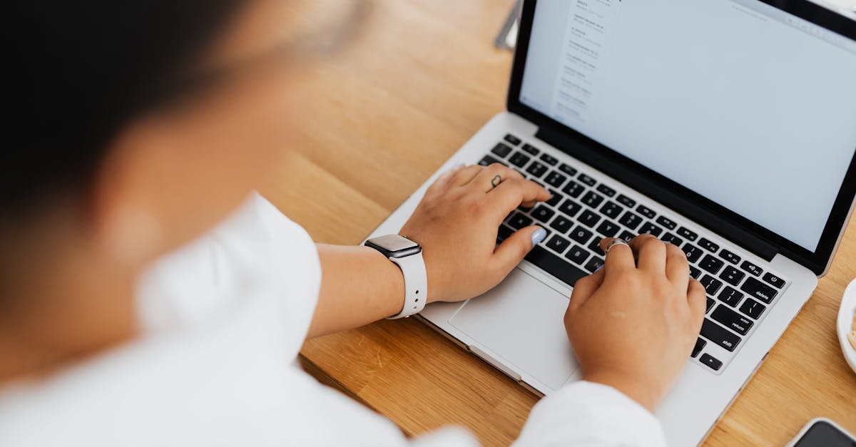High angle shot of a person typing on a laptop, focused on hands and keyboard.