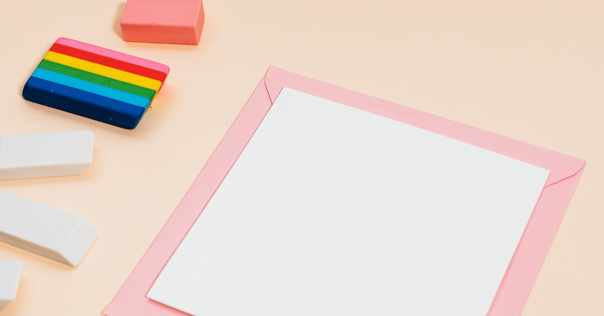 A flat lay of colorful erasers alongside a blank card and envelope on a pastel background.