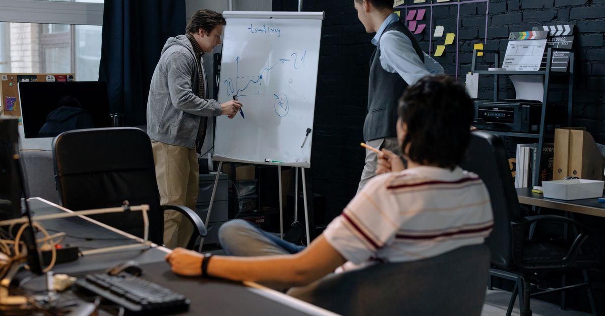 Business team in a modern office brainstorming ideas on a whiteboard. Engaged discussion and planning.